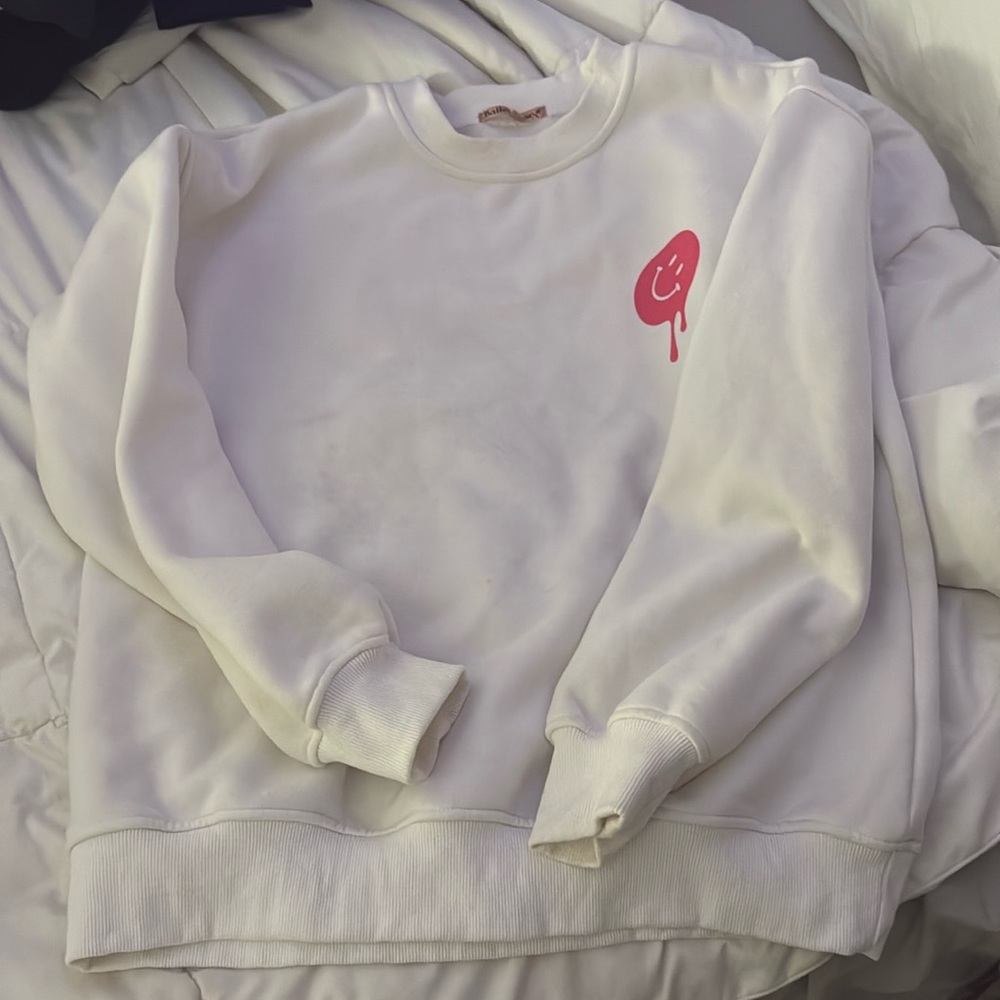 This is a white crewneck with pink smiley faces. It’s very soft and comfy!!